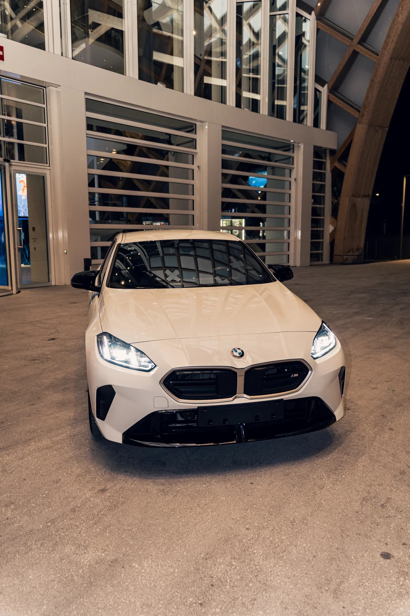 Face avant de la BMW M135 blanche, phares allumés