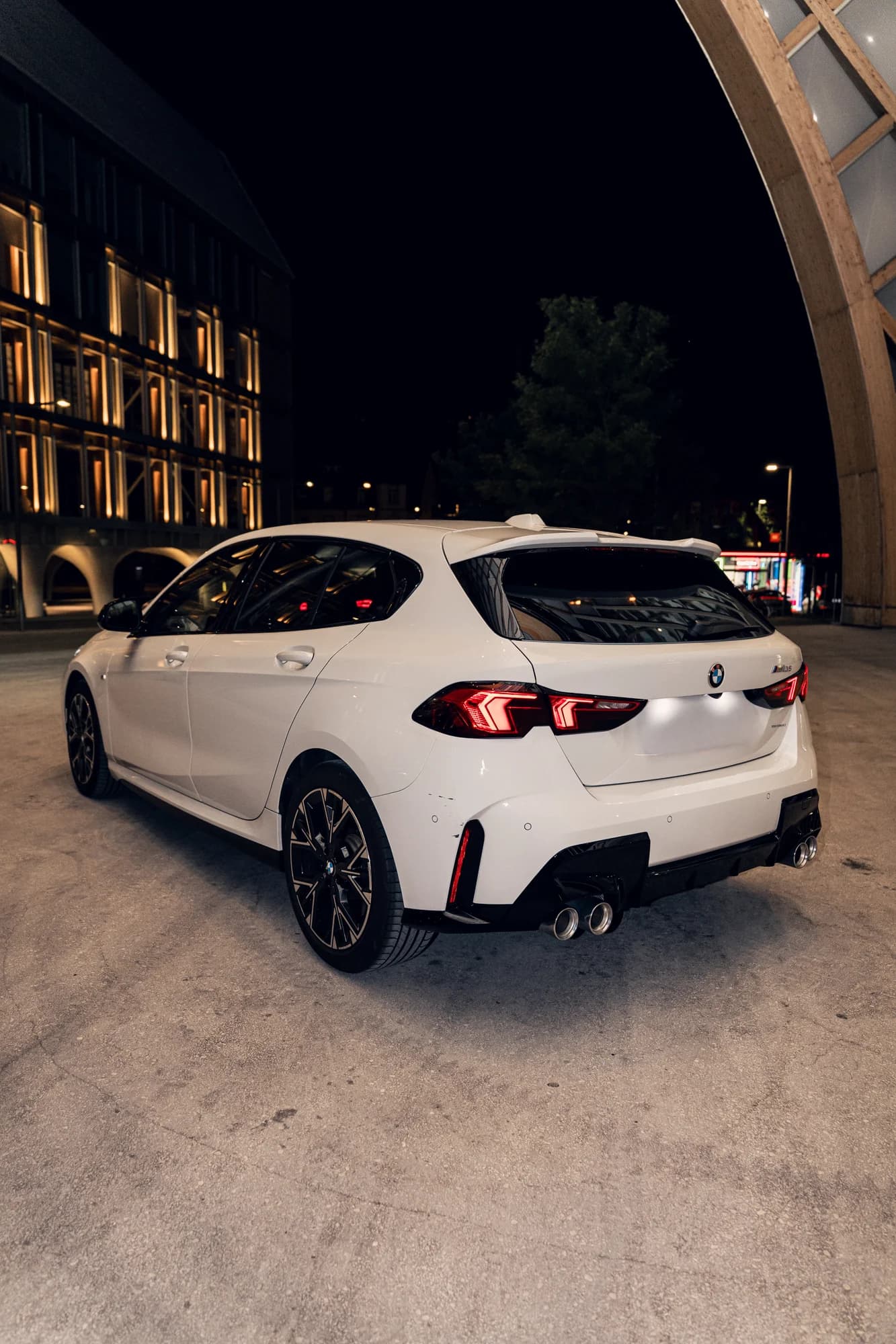 BMW M135 blanche de trois quarts arrière, feux allumés